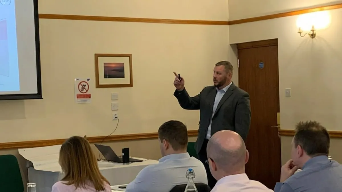 Gavin Thomas presenting to a training group seated at tables