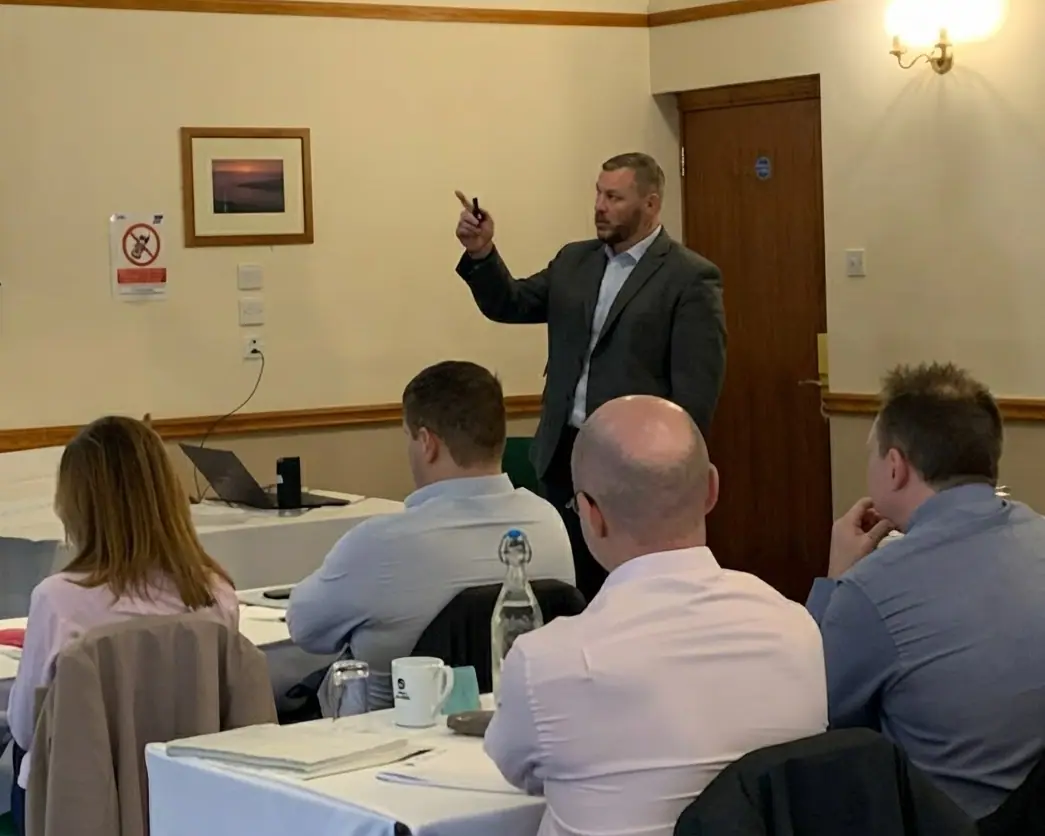 Gavin Thomas presenting to a training group seated at tables